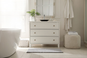 Stylish mat with pattern near chest of drawers in bathroom