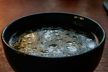 close up details of oil on water texture in blue soup bowl