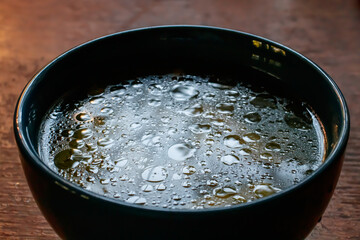 close up details of oil on water texture in blue soup bowl