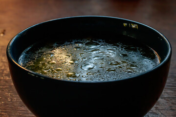 close up details of oil on water texture in blue soup bowl