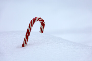Christmas candy cane in the snow. Background for New Year celebration, cold weather after snowfall