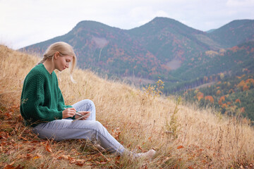 Naklejka na ściany i meble Young woman drawing on tablet in mountains, space for text