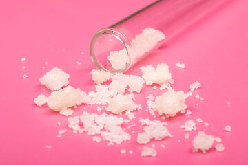 pieces of cannabis extract scattered close-up on a pink background with a glass jar