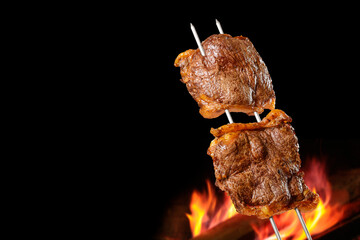 Barbecued Picanha barbecue with blurred fire in the background. Also called churrasco.