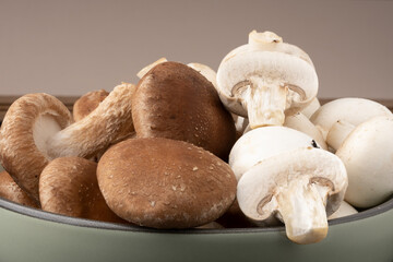 Champignon and shiitake mushrooms in a green bowl, selective focus.