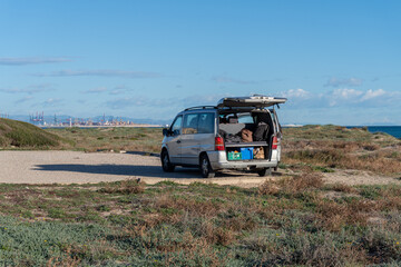 Campervan with the back door open, parked near the sea.