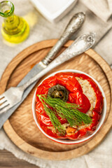 Homemade meat and rice stuffed bell peppers. Olive oil, sauce, cutlery on vintage wooden background