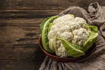 Beautiful cauliflower with green leaves in a ceramic bowl