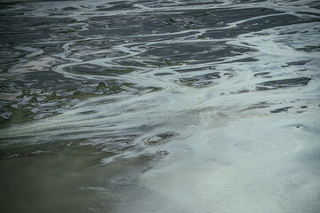Atmospheric landscape with many channels near shallow lake. Minimal backdrop of dark green water in shoal of mountain lake. Gloomy nature background of deep green water surface and many water streams.