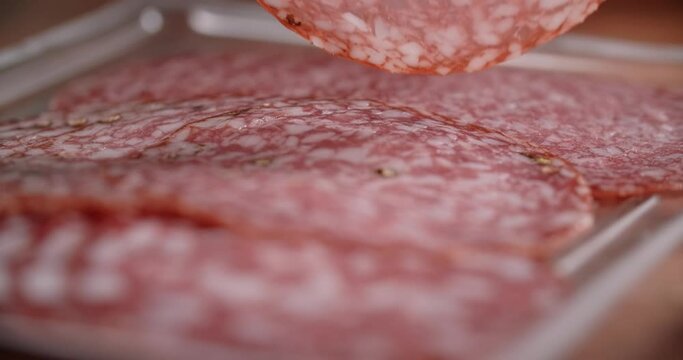 Woman takes thin slice of salami by fingers in slow motion. Cooking with pepperoni, 4k 60p Prores