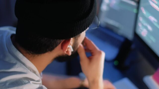 Young man mobile developer writes program code on a computer, programmer work in home office.