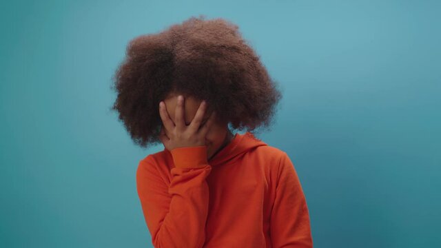 African American girl making face palm gesture expressing disbelief, exasperation, shame, irritation or annoyance standing on blue background.