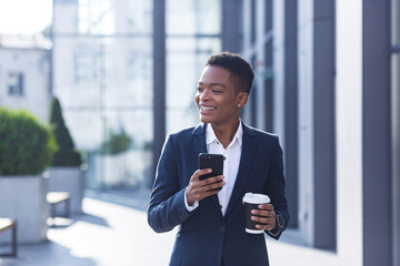 Business woman enjoys cellphone fun and smiling, African American boss businesswoman outside office in business suit