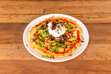 Pizza with burrata cheese, cherry tomatoes, arugula and serrano ham cooked in a stone oven