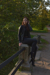 Naklejka na ściany i meble girl in a black leather jacket and black jeans in an autumn park