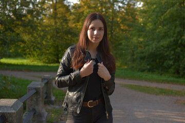 girl in a black leather jacket and black jeans in an autumn park