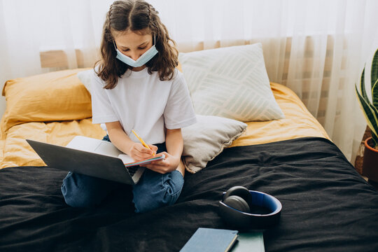 School girl studying at home wearing mask, distant learning