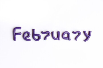 The word February is made of purple plasticine on a white background