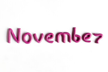 The word November is made of pink plasticine on a white background