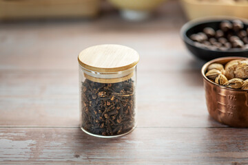 Glass jar with scented cloves vintage kitchen wooden table top