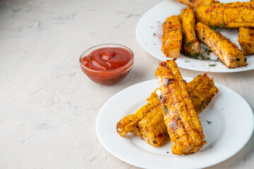 Grilled corn on the cob with barbecue sauce. Grilled corn ribs, on a white concrete plate.