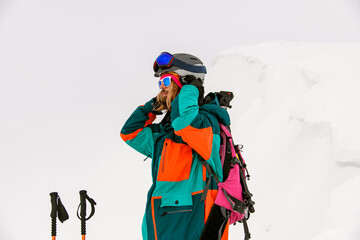 man skier in bright colorful ski suit and sunglasses against background of snow