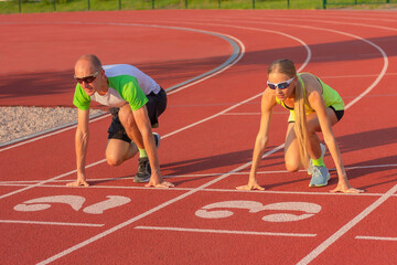 Athletic woman and man on the track of the stadium preparing for the start, starting to run....