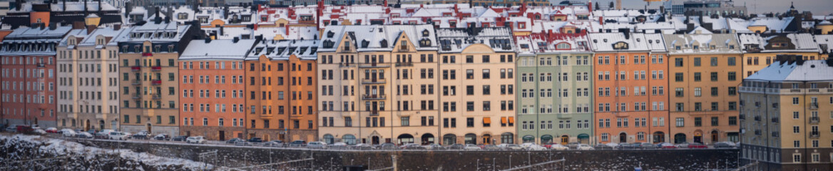 Fototapeta premium Panorama view over snowy and icy apartment buildings a cold and sunny pale winter day with snow in Stockholm
