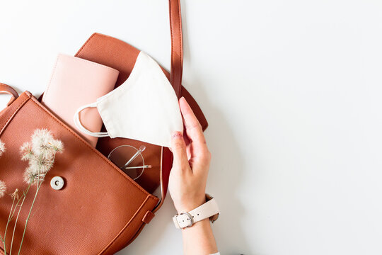 Women's fashion beige styled composition. Purse, mask, glasses, wallet on white background with copy space. Flat lay, top view. 