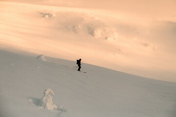 side view of a skier sliding down slope against background of snow