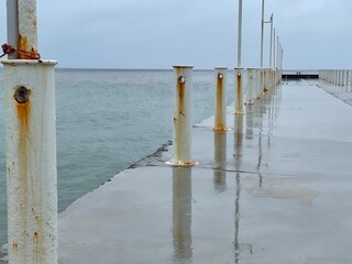 Wet concrete pier in the sea on a rainy day