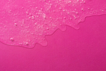 Background from cosmetic gel with bubbles,dripping down.Bright pink color,copy space for text or design.Top view,antibacterial liquid surface.Good as background or mockup.