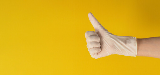 Hand do like hand sign and wear white latex gloves on yellow background.
