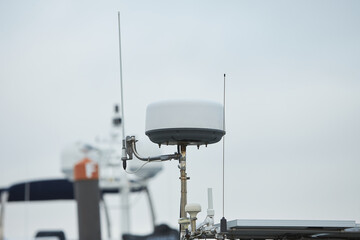 Upper part of a white luxury yacht with the navigational equipment on blue sky with clouds