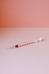 Pojedyncza strzykawka z igłą do szczepienia przeciwko Covid na pastelowym tle - obrazy, fototapety, plakaty