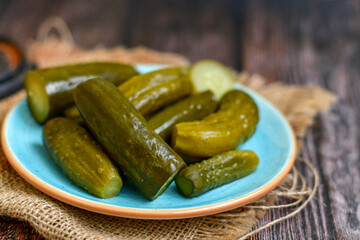  Plate of  homemade  organic bio pickled cucumbers  in vinegar with dill ,garlic and mustard seeds against dark rustic background
