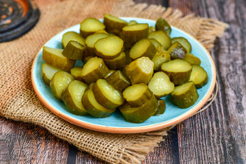  Plate of  homemade  organic bio pickled cucumbers  in vinegar with dill ,garlic and mustard seeds against dark rustic background
