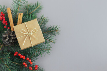 Craft gift box with spruce branch and red berries on a grey background. Holiday concept.