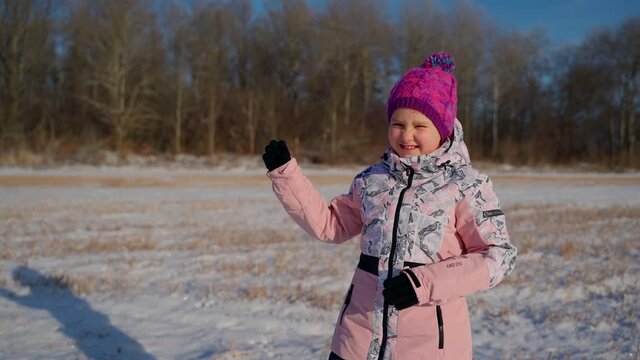 Cute girl dancing at winter and looking at camera outdoors. Female child dancer having fun outside. Positive face emotions. Leisure activity and happy childhood concept