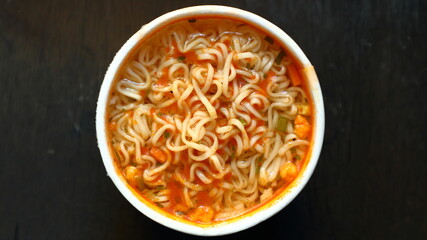 Top view of instant noodles in cup on wooden background