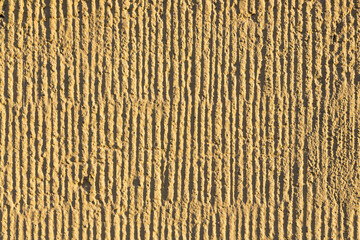 Texture of the wall. Decorative plaster. Rough painted surface with a pattern of vertical stripes, recesses and dents. Great for background and design. Close-up.