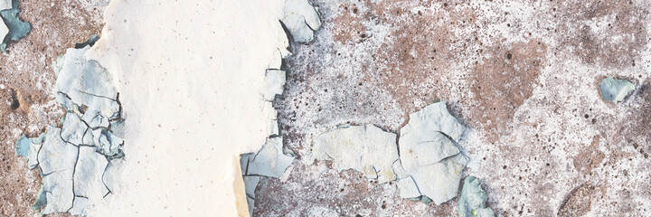 Peeling paint on the wall. Panorama of a concrete wall with old cracked flaking paint. Weathered...