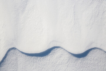 Beautiful winter background with snowy ground. Natural snow texture. Wind sculpted patterns on snow surface. Closeup top view with copy space.