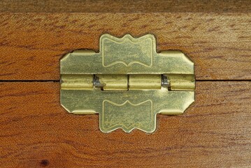 one small yellow brass hinge on a brown wooden box board - obrazy, fototapety, plakaty