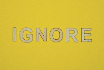word ignore made from wooden letters lies on a yellow table
