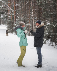Fototapeta na wymiar Happy young couple having fun in snow and walking in winter forest