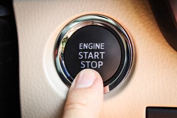 Pressing push start button in a car. Close-up of finger pressing the engine start button.