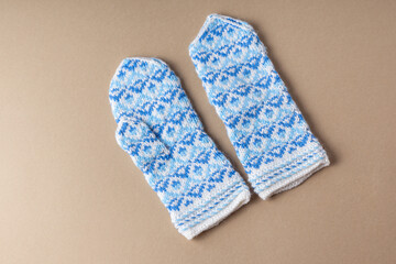 Knitted mittens on beige background. Warm handmade mittens for winter. Top view