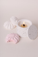 Fototapeta na wymiar Coconut wax candle in white concrete cup with lid. Marshmallow scented candle