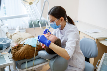 A female dentist treats tooth decay on a male patient's teeth at a dental clinic during the...